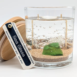 Glass candle with ocean-themed design and wooden lid on a white background