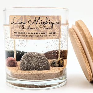 Candle jar with sand and rocks inside, labeled 'Lake Michigan Charlevoix Stone', on a white background.